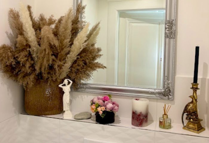 Elegant decor at Massage Just For You, Budapest. Vase with pampas grass, statue, flowers, candle, diffuser, & bird candle holder.
