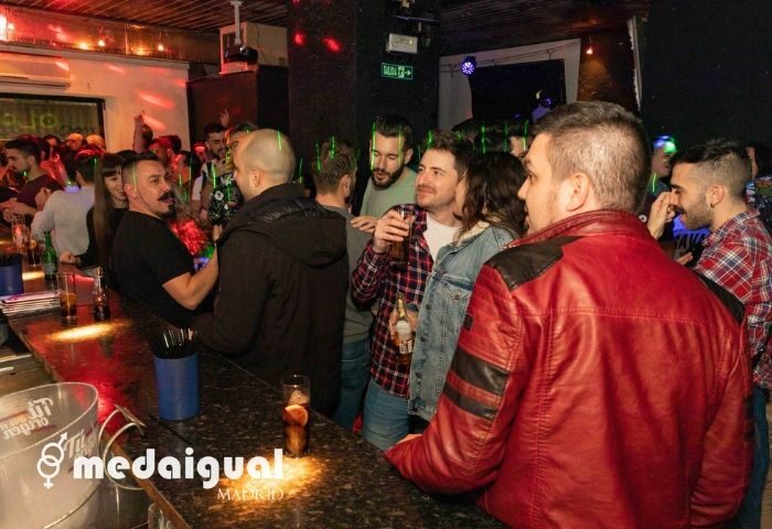 Medaigual Gay Bar in Madrid's Chueca district. Crowded scene with men at the bar, drinks visible. Nightlife, gay travel, Madrid.