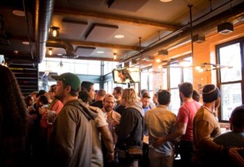 Meeting House Tavern, a unique gay bar in Chicago. Interior view of a crowded bar with men socializing. Gay travel advice.