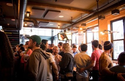Meeting House Tavern, a unique gay bar in Chicago. Interior view of a crowded bar with men socializing. Gay travel advice.