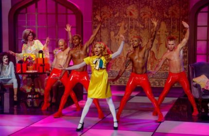 Meeting House Tavern, a unique gay bar in Chicago, features drag queens and shirtless dancers in red pants on a pink stage.