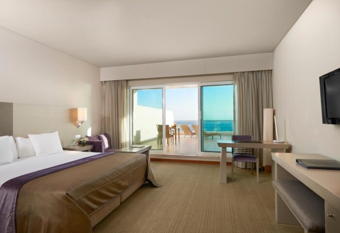 Meliá Madeira Mare Hotel room. Gay travel advice. Balcony view of the ocean, bed, desk, and tv. Meliá Madeira Mare Hotel interior.