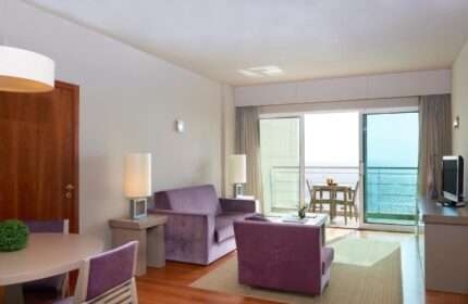 Meliá Madeira Mare room. Hotel room interior with purple seating and a balcony overlooking the ocean. Gay travel Madeira.