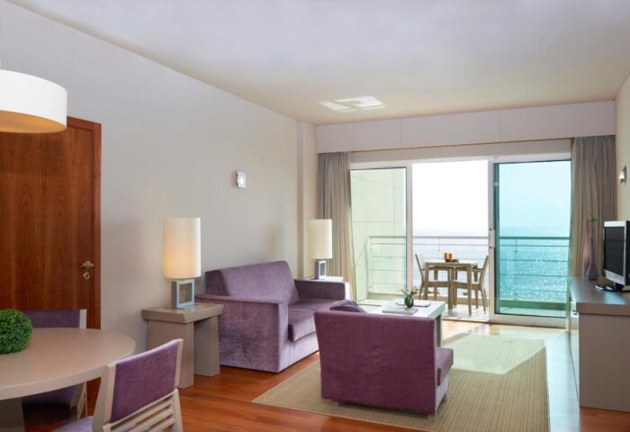 Meliá Madeira Mare room. Hotel room interior with purple seating and a balcony overlooking the ocean. Gay travel Madeira.
