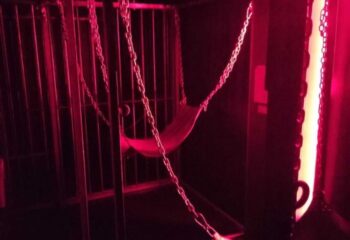 Interior of a Men Factory gay cruise club in Barcelona. Cage with chains and a hammock, lit with red light. Gay travel.