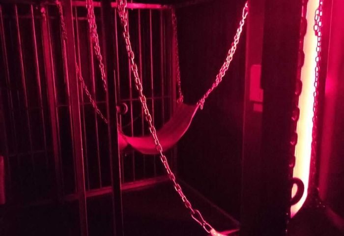 Interior of a Men Factory gay cruise club in Barcelona. Cage with chains and a hammock, lit with red light. Gay travel.