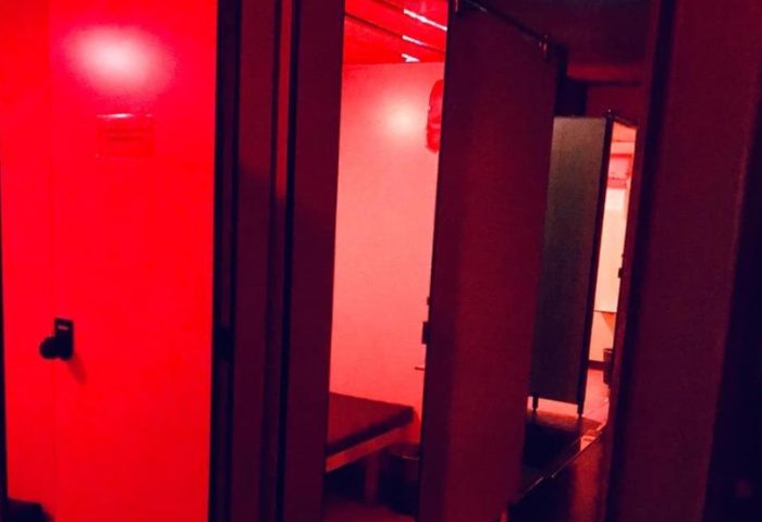 Interior of Metro Sauna Centrale Milan, a gay sauna. Red lighting illuminates private cabins with benches. Gay travel advice.