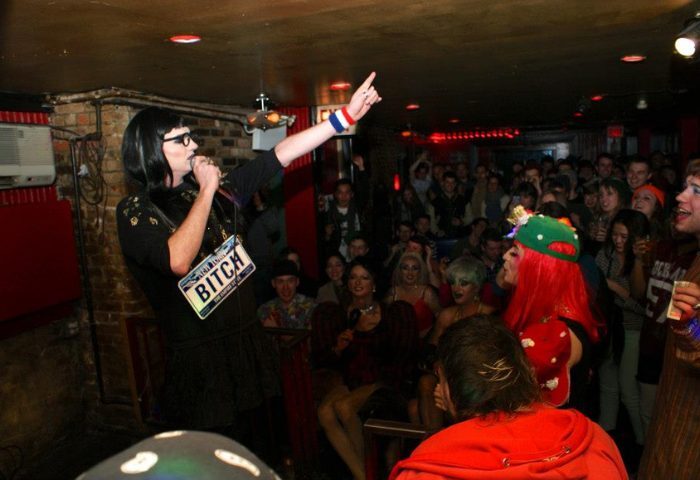 Drag queen performs at Metropolitan Bar, a queer bar in New York. Crowd enjoys the show. Gay travel advice.