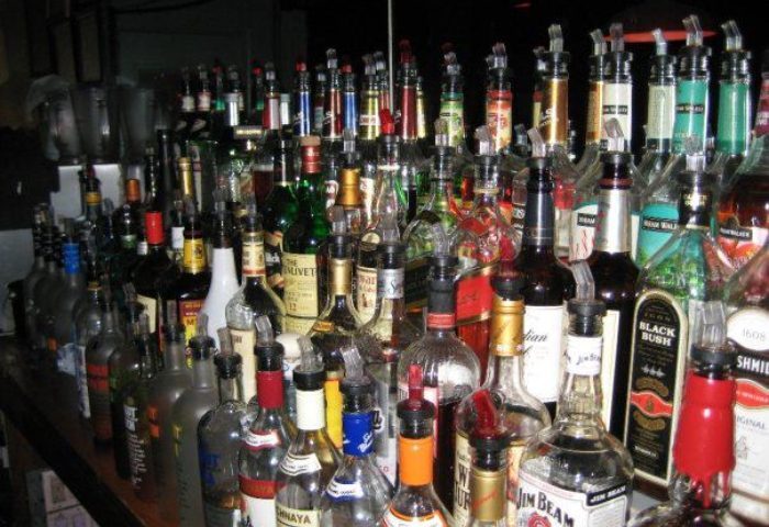 A full bar at a Metropolitan bar for queers in New York. Many liquor bottles with pourers are displayed at this gay bar.