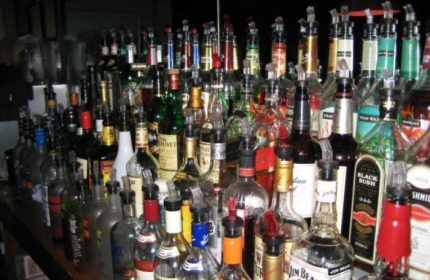 A full bar at a Metropolitan bar for queers in New York. Many liquor bottles with pourers are displayed at this gay bar.