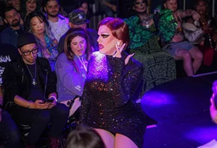 Drag queen performing at Micky's West Hollywood, a popular gay bar. The performer is wearing a sparkly black dress, red hair, and makeup.