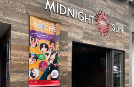 Midnight Sun Video Bar in San Francisco. Signage and a banner advertising Media Noche with drag queens and Latinx gogos. Gay travel advice.