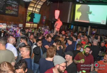Midnight Sun Video Bar in San Francisco: A packed gay bar with men, drinks, and a dancer on a platform. A popular gay travel destination.