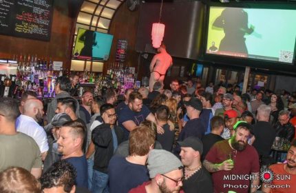 Midnight Sun Video Bar in San Francisco: A packed gay bar with men, drinks, and a dancer on a platform. A popular gay travel destination.