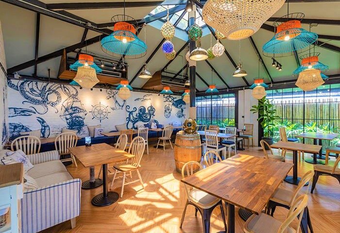 Holiday Inn Express Krabi Ao Nang Beach's modern design. Gay Krabi beach hotel interior with nautical decor, tables, and chairs.