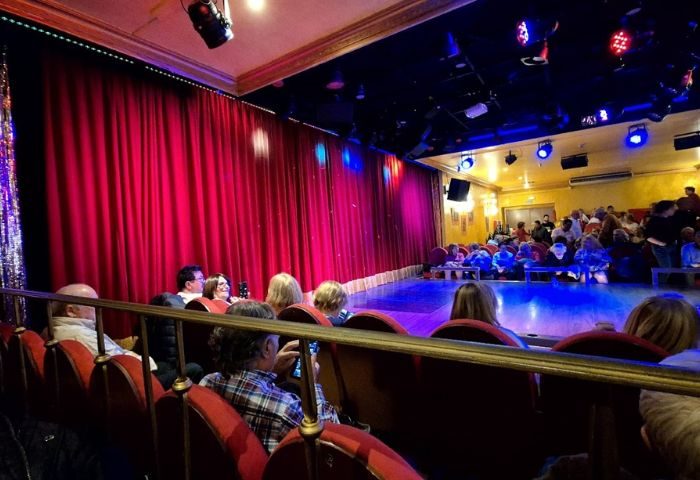Molino Benidorm theater interior. Red curtains, stage lights, and audience seating. Gay live shows in Benidorm for gay men travel.