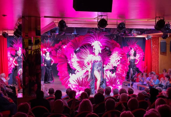 Molino Benidorm gay live shows. Drag queens perform on stage with feather costumes in Benidorm, Spain. Audience watching.