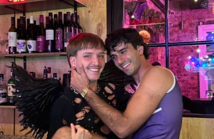 Two gay men smile at Mollie's Bar and Diner in Melbourne. One wears angel wings. Gay travel advice for Melbourne, Australia.