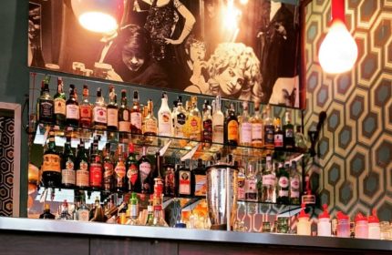 Mono Bar Milan: A stylish bar with shelves full of liquor bottles, vintage decor, and a retro vibe. A gay-friendly destination.