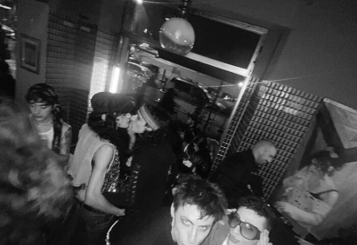 Milan gay bar scene: Black and white shot of a crowded Mono Bar, with two men kissing and others enjoying the nightlife.