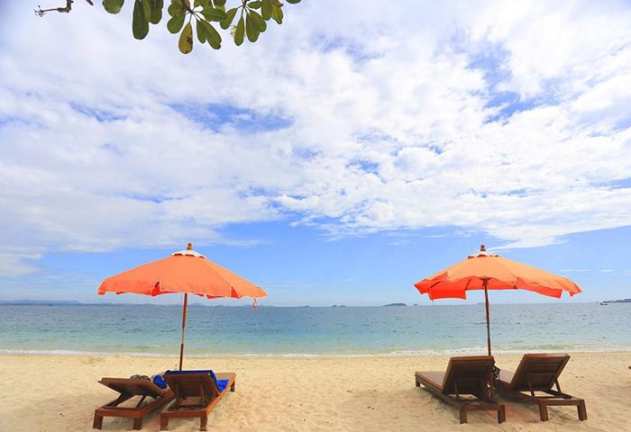 Mooban Talay Resort, Koh Samet. Beach view with orange umbrellas and lounge chairs. Best beach retreat, quiet gay hotel.
