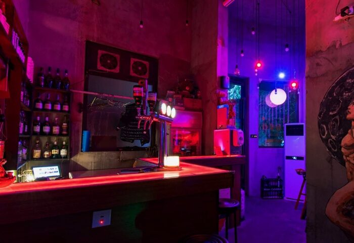 Interior of Moon Bar in Shanghai, a gay-friendly travel destination, featuring a bar with red lighting and a purple-lit doorway.