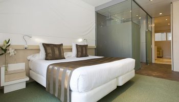 Ako Suites Hotel Barcelona bedroom. Best gay serviced apartment in Eixample gayborhood. Modern design with glass-enclosed shower.