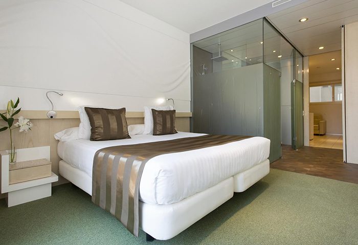 Ako Suites Hotel Barcelona bedroom. Best gay serviced apartment in Eixample gayborhood. Modern design with glass-enclosed shower.
