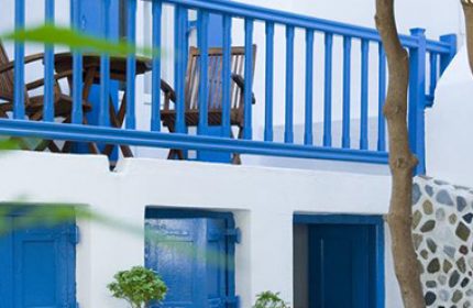 Mykonos Matina Hotel: Budget gay hotel featuring white walls, blue accents, a balcony with chairs, and potted plants. A charming Greek island stay.