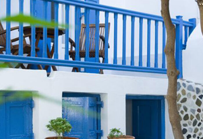 Mykonos Matina Hotel: Budget gay hotel featuring white walls, blue accents, a balcony with chairs, and potted plants. A charming Greek island stay.