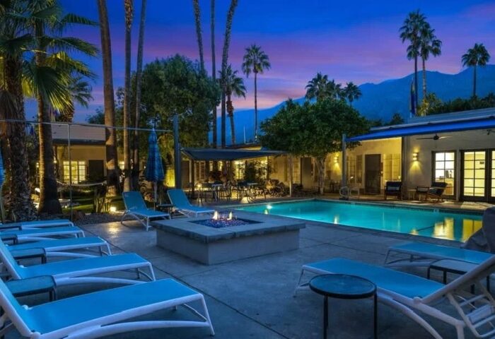 Desert Paradise Resort Hotel pool and fire pit at dusk. Palm Springs gay men's hotel for big group. Budget-friendly travel destination.