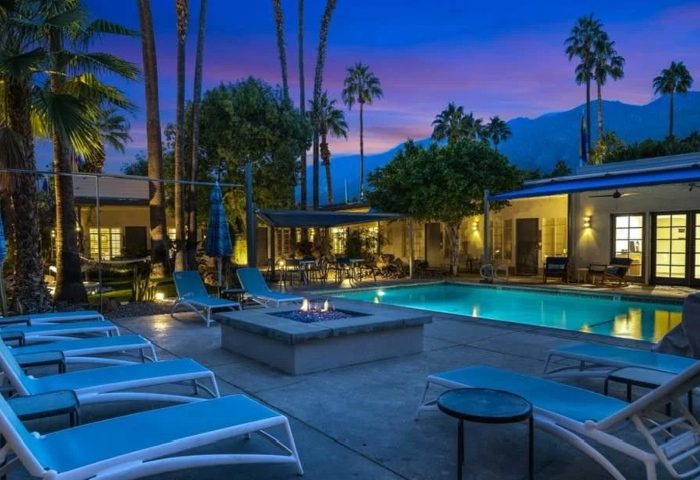 Desert Paradise Resort Hotel pool and fire pit at dusk. Palm Springs gay men's hotel for big group. Budget-friendly travel destination.
