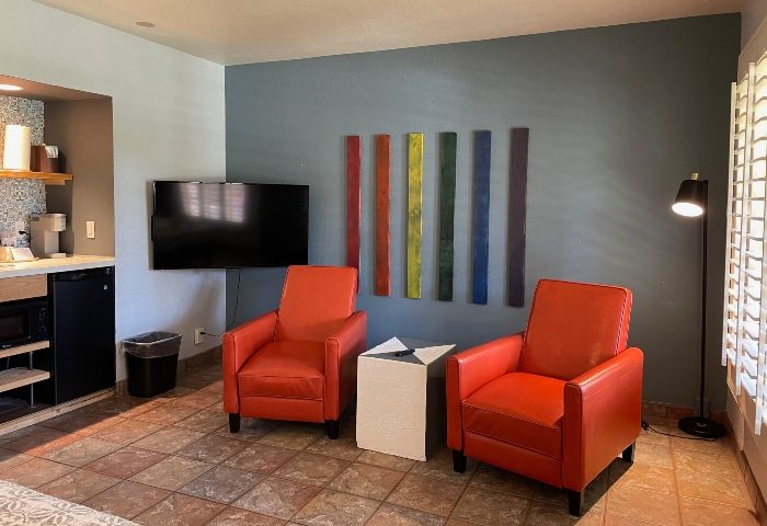 Desert Paradise Resort Hotel room. Budget gay men hotel in Palm Springs. Room with rainbow art, chairs, and TV. Interior design.