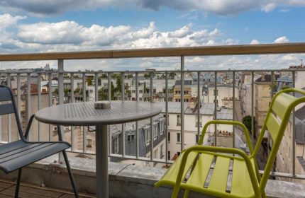 Hotel Jules & Jim, most booked gay adult-only hotel in Paris. Balcony view with table and chairs overlooking the city skyline.