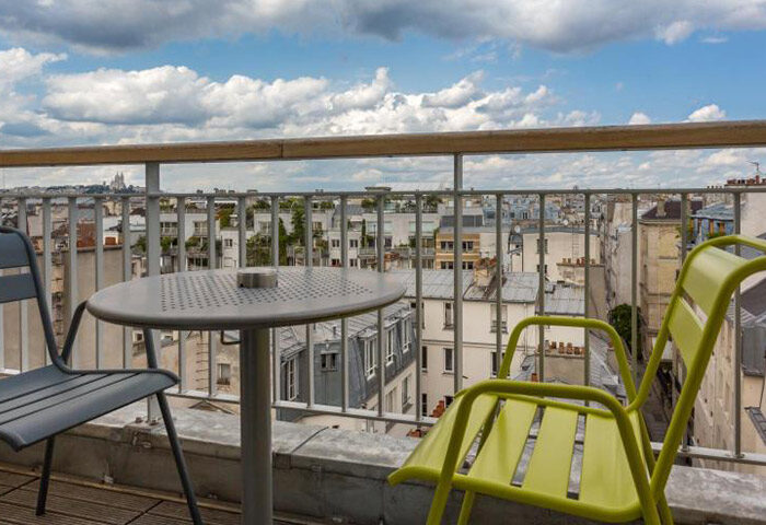 Hotel Jules & Jim, most booked gay adult-only hotel in Paris. Balcony view with table and chairs overlooking the city skyline.