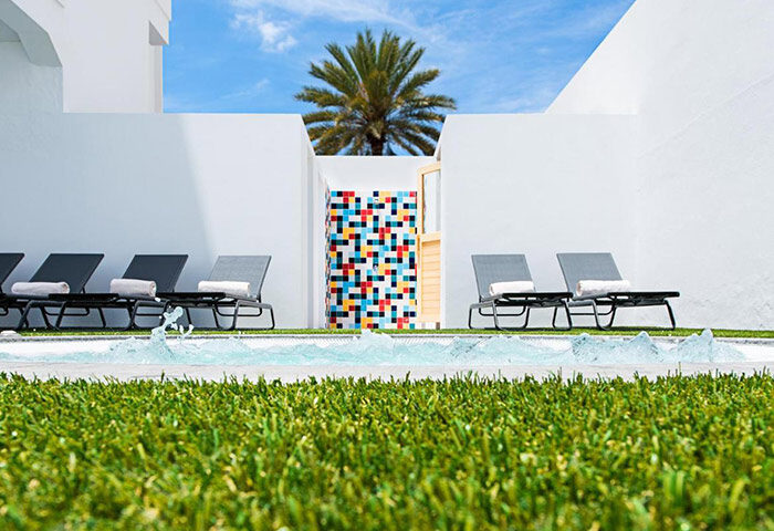 AxelBeach Maspalomas, Gran Canaria. Gay adults-only hotel poolside view with sunbeds, palm tree, and colorful design. Modern apart and lounge club.