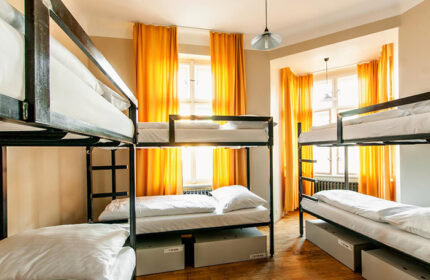Czech Inn, most-booked gay-friendly hostel in Prague. Dorm room with bunk beds, storage, yellow curtains, and hardwood floors. Great for gay nightlife.