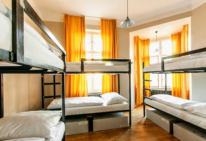Czech Inn, most-booked gay-friendly hostel in Prague. Dorm room with bunk beds, storage, yellow curtains, and hardwood floors. Great for gay nightlife.