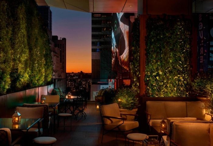 Times Square EDITION: Outdoor terrace at dusk. Gay-friendly hotel in Hells Kitchen, New York. Cozy seating, city views.