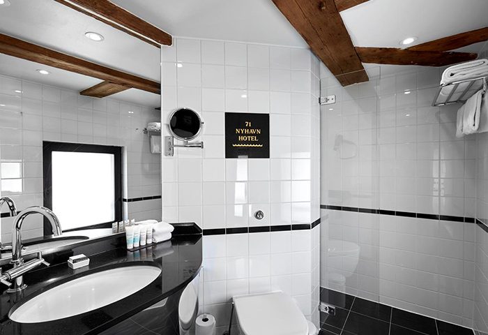 Bathroom at 71 Nyhavn Hotel, Copenhagen. A most-booked gay honeymoon hotel with modern fixtures, black and white tile, and exposed wooden beams.