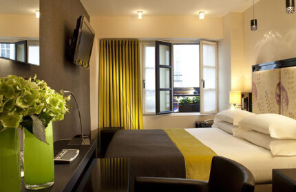 Hotel Caron, a most-booked gay honeymoon hotel in Paris's Marais gayborhood. Room view with bed, open window, and stylish decor.
