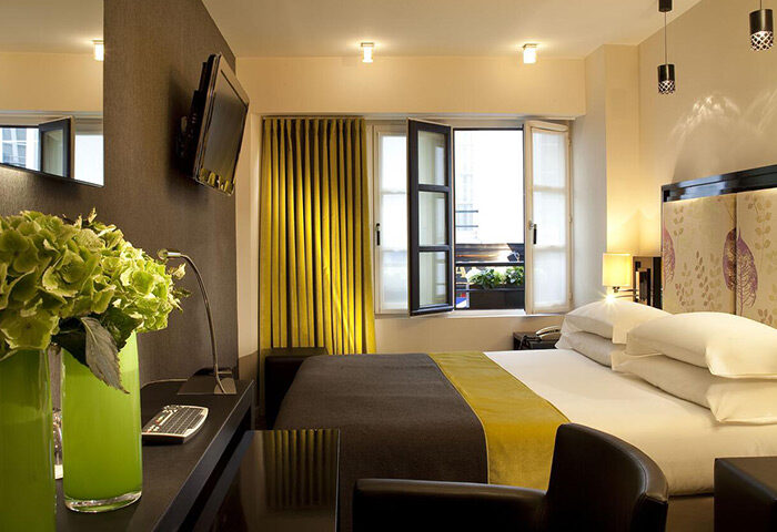 Hotel Caron, a most-booked gay honeymoon hotel in Paris's Marais gayborhood. Room view with bed, open window, and stylish decor.