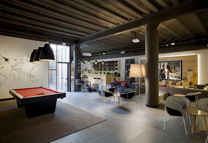 TOC Hostel Barcelona's common area. Pool table, bar, seating areas, and a large screen TV. A top gay hostel for solo gay travelers.