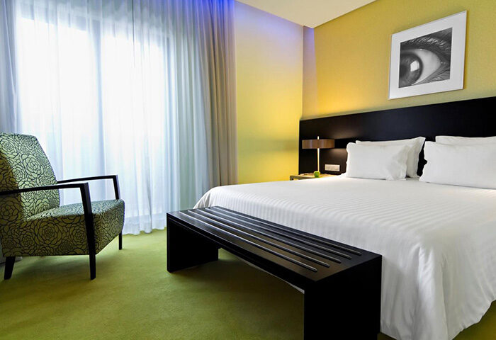 SANA Capitol Hotel room in Lisbon. Modern decor, chair, bed, and bench. A most booked gay hotel near a gay dance club.