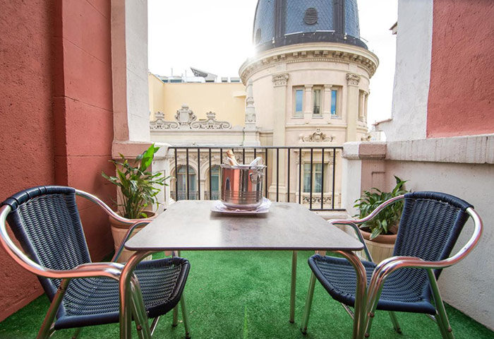 Petit Palace Chueca, Madrid: Balcony view with table, chairs, and champagne. A top-booked gay hotel in Madrid city center.