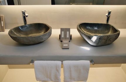 Ilio Maris gay hotel Mykonos: Stone sinks, towels, and toiletries in a modern bathroom. Near gay bars in Mykonos Town.