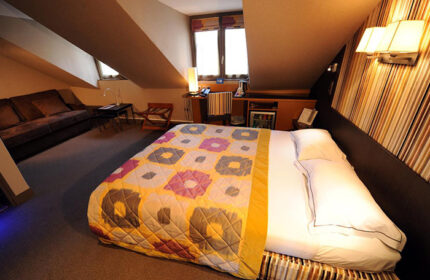Hotel Du Vieux Saule, Paris. Cozy room in Marais gayborhood. Bed with colorful quilt, sofa, desk. Most-booked gay hotel in Paris.