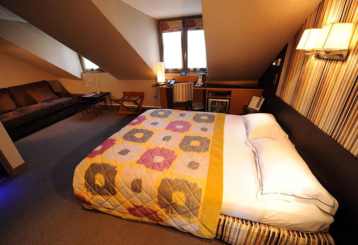 Hotel Du Vieux Saule, Paris. Cozy room in Marais gayborhood. Bed with colorful quilt, sofa, desk. Most-booked gay hotel in Paris.