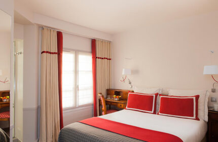 Hotel de la Place du Louvre room. Gay hotel in Paris Marais gayborhood. Red and beige decor, desk, bed, and window. Most booked hotel.