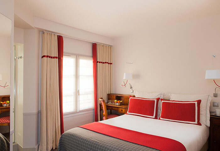Hotel de la Place du Louvre room. Gay hotel in Paris Marais gayborhood. Red and beige decor, desk, bed, and window. Most booked hotel.